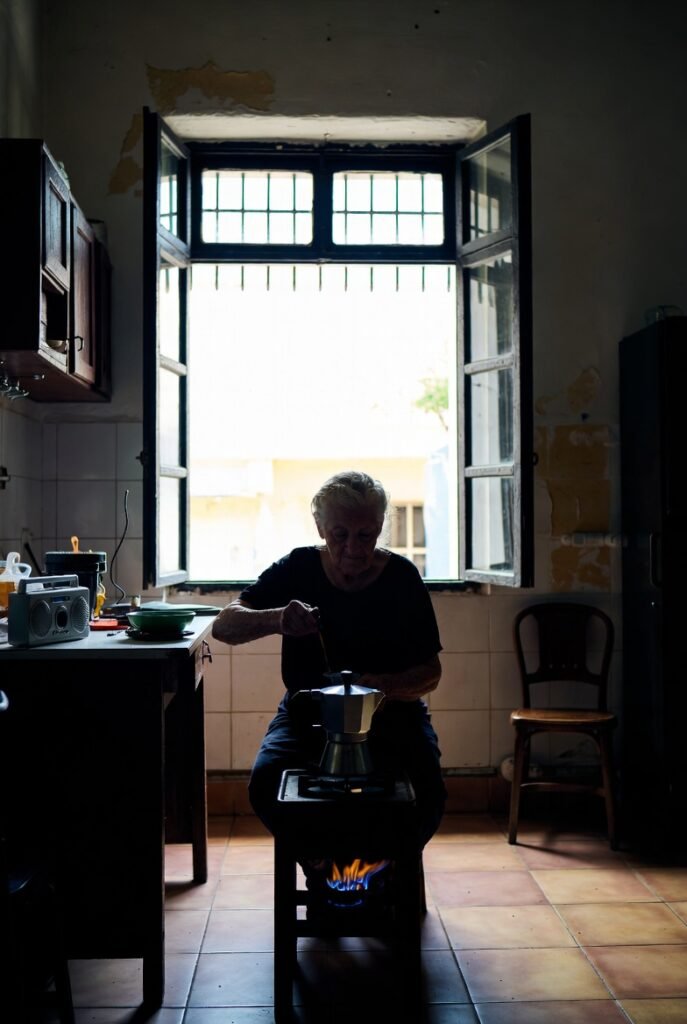 Cuban elderly woman preparing coffee by hand during total island-wide power blackout in Havana Cuba March 2026 as US oil blockade triggered energy crisis leaving 10 million without electricity