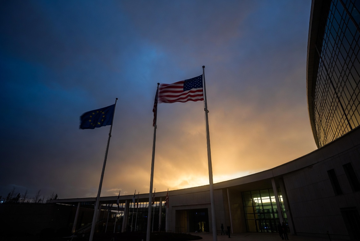 US and EU flags at an international summit building representing transatlantic alliance tensions in 2026