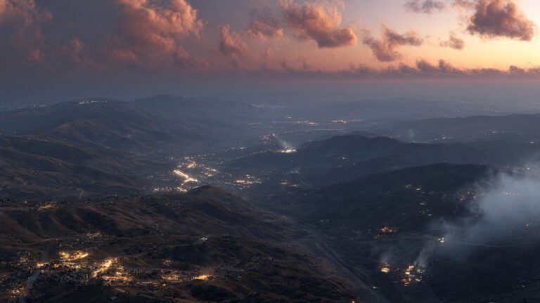 Aerial view of the Israel-Lebanon border at dusk with smoke rising in the distance, April 2026