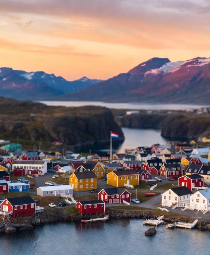 Aerial view of Nuuk, Greenland at sunset with Greenlandic flag and Arctic fjord backdrop — Greenland independence debate 2026