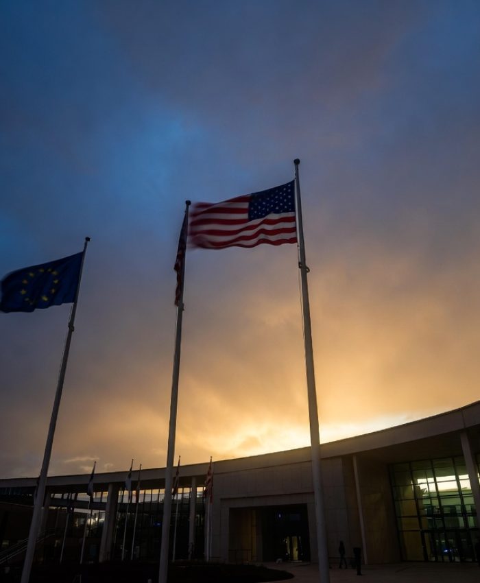 US and EU flags at an international summit building representing transatlantic alliance tensions in 2026
